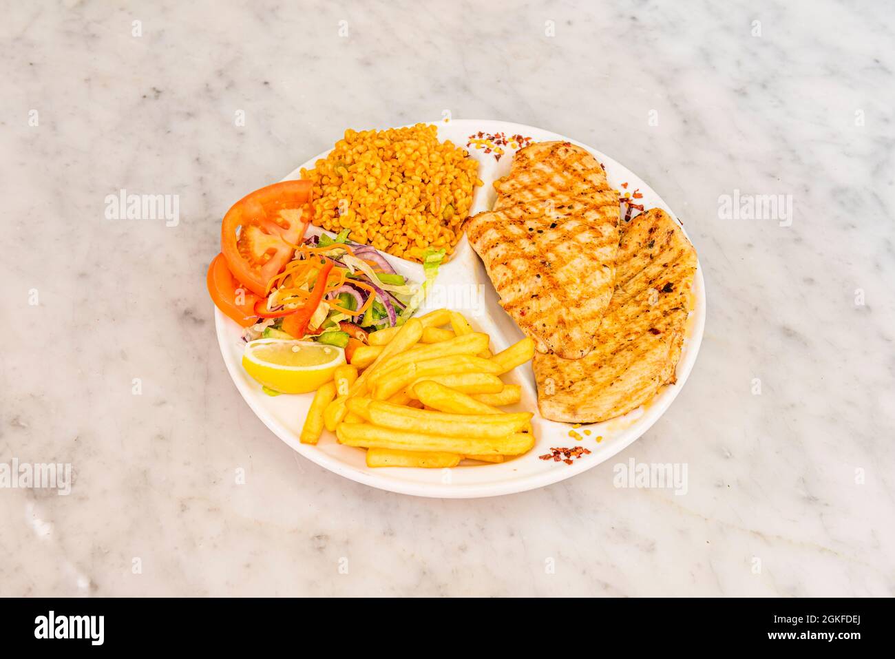 Menu plate in a Turkish restaurant with chicken fillet and side dishes of chips, salad and bulgur Stock Photo