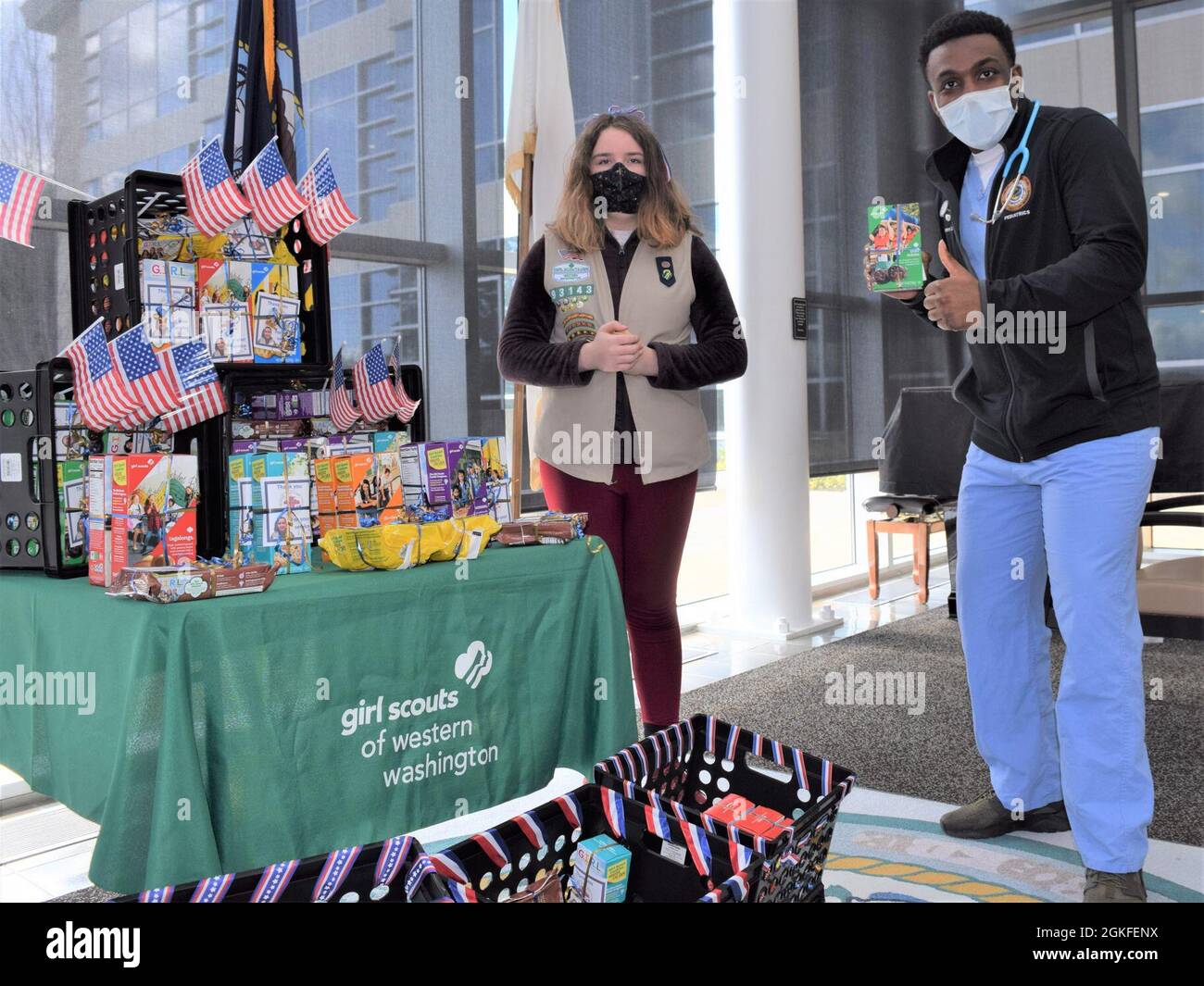 A thin mints thumbs-up…Hospital Corpsman 3rd Class Vincent Jackson, assigned to NHB/NMRTC Bremerton Pediatrics Department receives a box of Girl Scout cookies, donated from Local Girl Scout Rene Vollmuth, the daughter of Robert and Sheri L. Vollmuth, employees at Puget Sound Naval Shipyard & Intermediate Maintenance Facility. Rene donated over 118 boxes – one for each year the hospital has been on land - of Girl Scout cookies to Naval Hospital Bremerton staff, April 8, 2021 Stock Photo