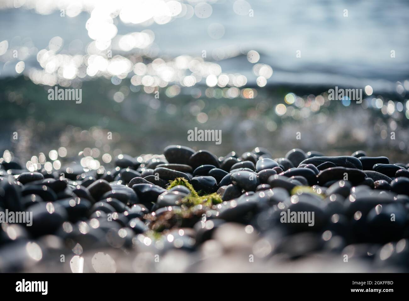 Beach pebbles close-up with foamy waves hitting the shore calm and tranquil summer background, clean sea water of Mediterranean Sea in the morning Stock Photo