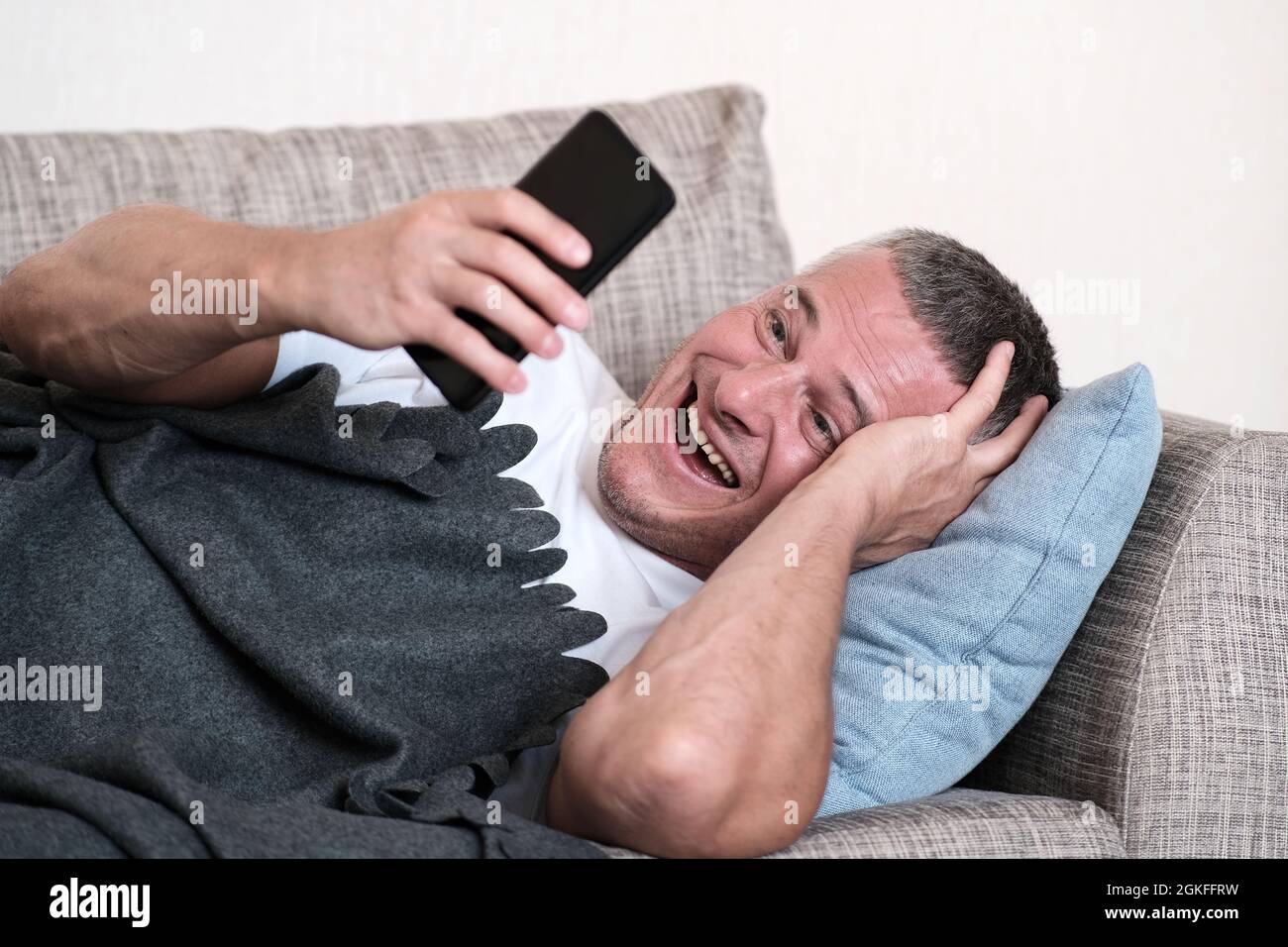 A beautiful portrait of a man laughing while looking at a smartphone. Mobile communication. Online communication Stock Photo