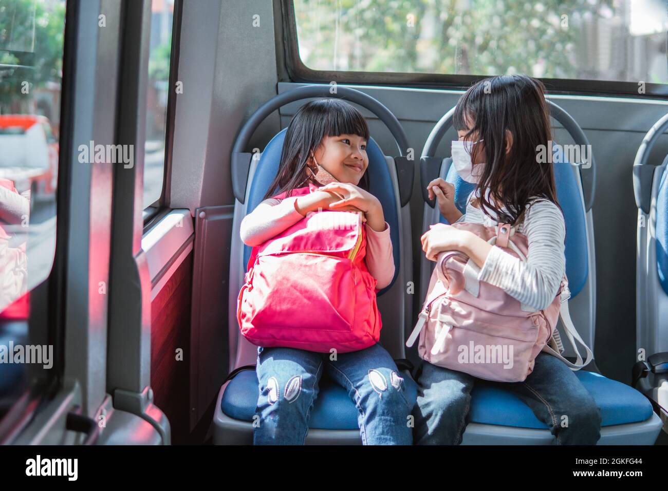 two asian primary student going to school by bus public transport Stock