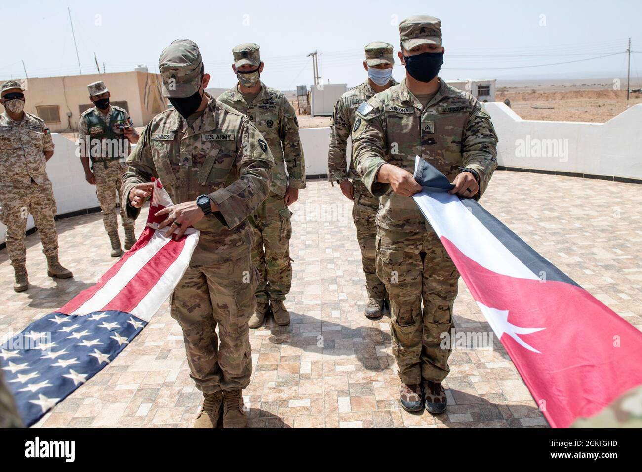 The Jordanian Armed Forces, Southern Command, 3rd Border Guard Group Commander, Col. Ra'ad Al Aamayra, and Task Force Spartan Division Tactical- Jordan Officer in Charge, Col. Christopher Fletcher, exchange flags in a symbolic gesture of friendship and partnership following the successful completion of the Desert Warrior 21 live-fire exercise, April 8, 2021. The exercise was viewed by JAF General Officers and senior leaders from U.S. Army Central and TF Spartan. Moments of expressed gratitude help to solidify the enduring relationship between the two forces. Stock Photo