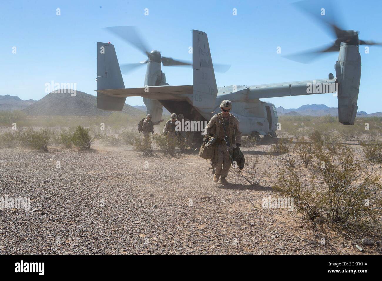 A U.S. Marine with Echo Company, 2nd Battalion, 4th Marine Regiment, 1st Marine Division, disembarks an MV-22B Osprey, assigned to Marine Aviation Weapons and Tactics Squadron One (MAWTS-1), during Weapons and Tactics Instructor (WTI) course 2-21, at Landing Zone Mallard, in Luke Air Force Range, Ariz., April 9, 2021. The WTI course is a seven-week training event hosted by MAWTS-1, providing standardized advanced tactical training certification of unit instructors qualifications to support Marine aviation training and readiness, and assists in developing and employing aviation weapons and tact Stock Photo
