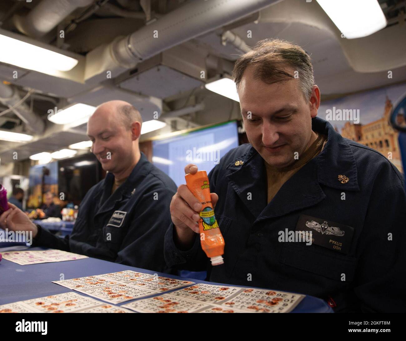 210411-N-CJ510-0030 MEDITERRANEAN SEA (April 11, 2021) Chief Cryptologic Technician (Collection) William Pykus, left, stamps a bingo card on the mess decks of the Arleigh Burke-class guided-missile destroyer USS Roosevelt (DDG 80) during a game of bingo, April 11, 2021. Roosevelt, forward-deployed to Rota, Spain, is on its second patrol in the U.S. Sixth Fleet area of operations in support of regional allies and partners and U.S. national security interests in Europe and Africa. Stock Photo