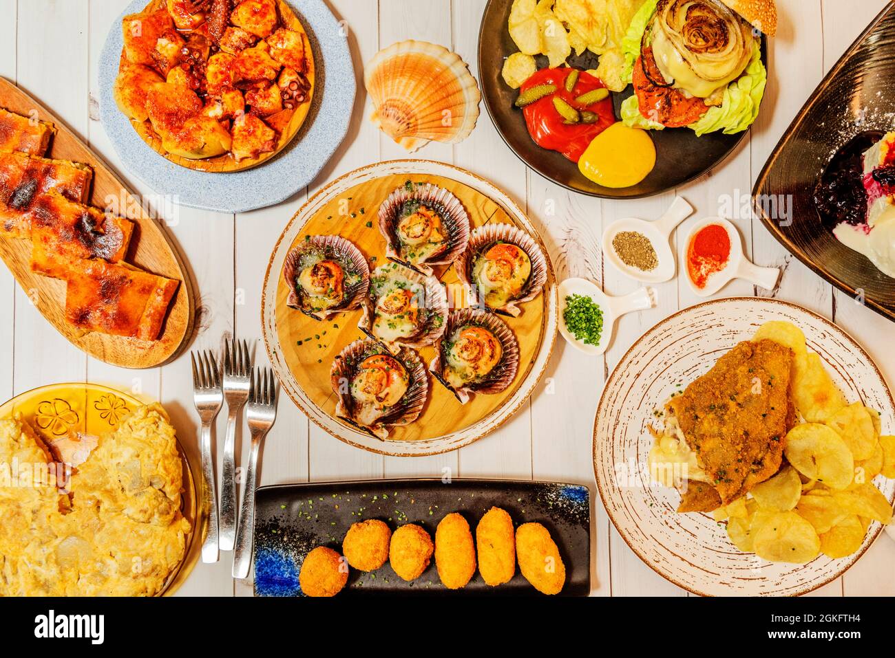 top view of typical Spanish food dishes with real empanada, scallops, Galician octopus, escalope, croquettes and Spanish potato omelette Stock Photo