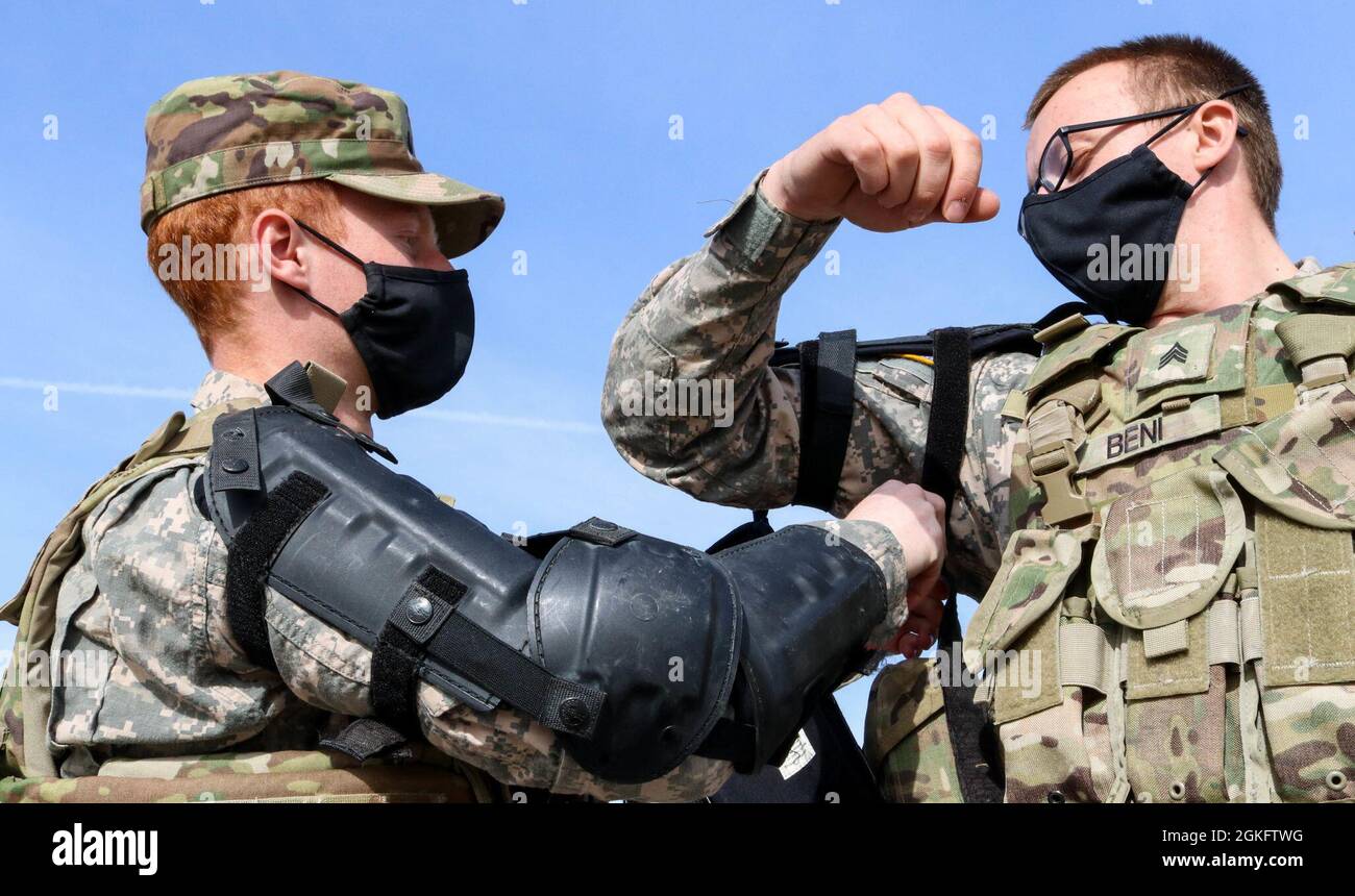 Pfc. Hayden Pratt straps a protective shoulder pad on to Sgt. Nathanael  Beni before fire phobia training at Camp Novo Selo, Kosovo, on April 12,  2021. The cavalry scouts are assigned to