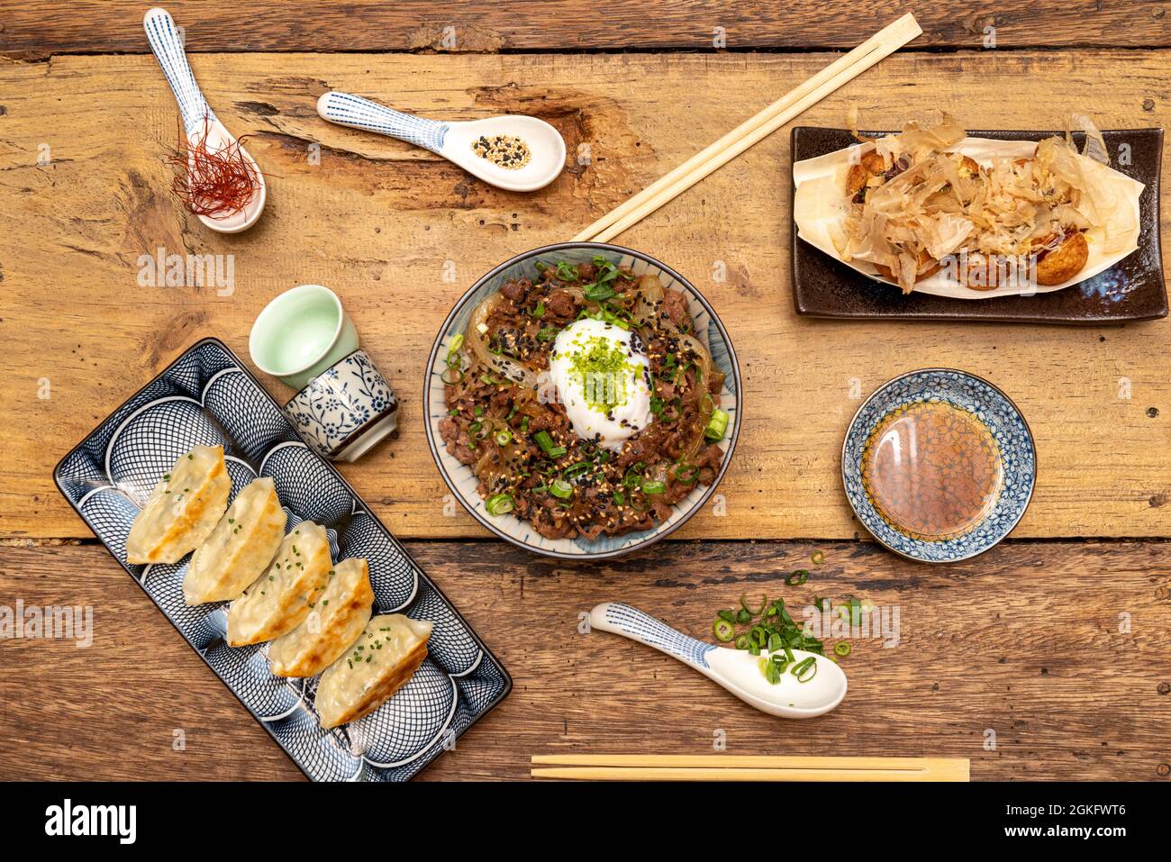 Japanese ramen with takoyaki and gyozas presented in typical Japanese dishes on wooden table Stock Photo