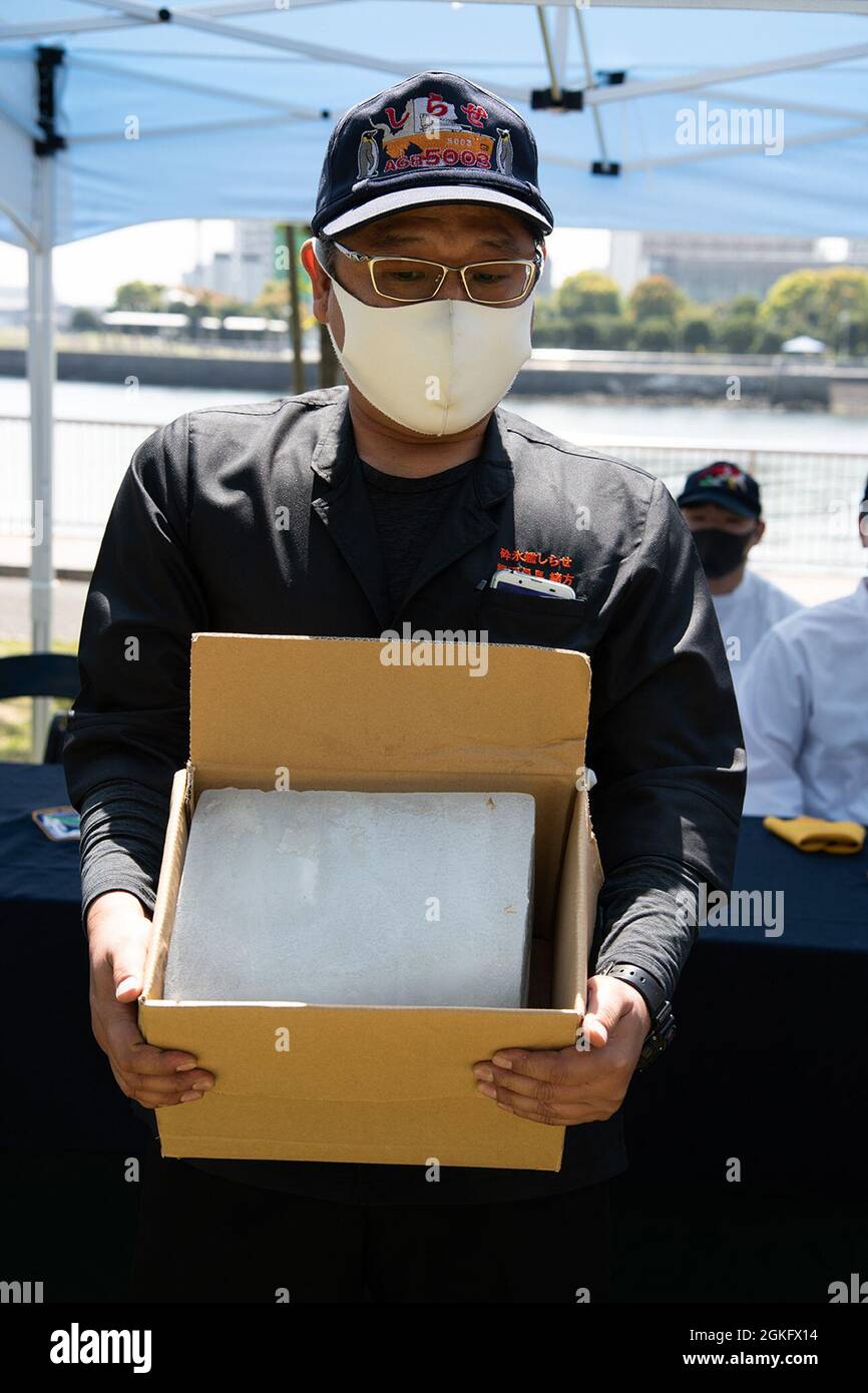 YOKOSUKA, Japan (April 12, 2021) — Japan Maritime Self-Defense Force (JMSDF) Chief Culinary Specialist Hiroyuki Ogata, attached to JMSDF ice breaker JS Shirase (AGB 5003), holds an ice block from Antarctica during Commander, Fleet Activities Yokosuka’ (CFAY) Dessert Bake-Off. Ogata presented the rare block of ice as a thank you for participating in CFAY’s desert challenge. Rear Adm. Brian Fort, Commander, U.S. Naval Forces Japan/Commander, Navy Region Japan challenged Navy installations across Japan to create an American dessert inspired by Japanese ingredients. For more than 75 years, CFAY ha Stock Photo