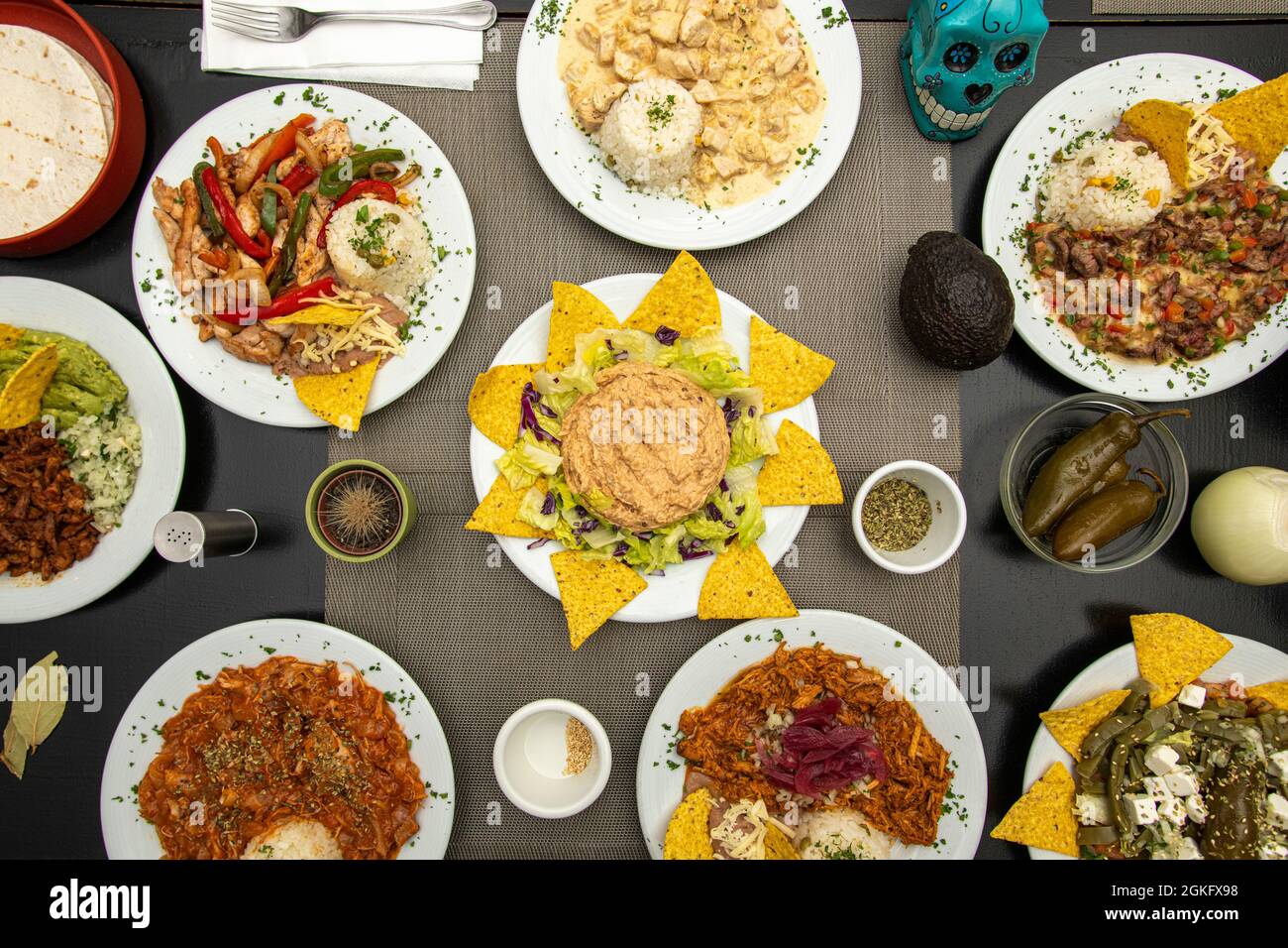 Set of Mexican food dishes with fajitas, peppers, corn chips, chicken tinga stew, pumpkin flower chicken, nopales with cheese, ripe avocado and jalape Stock Photo