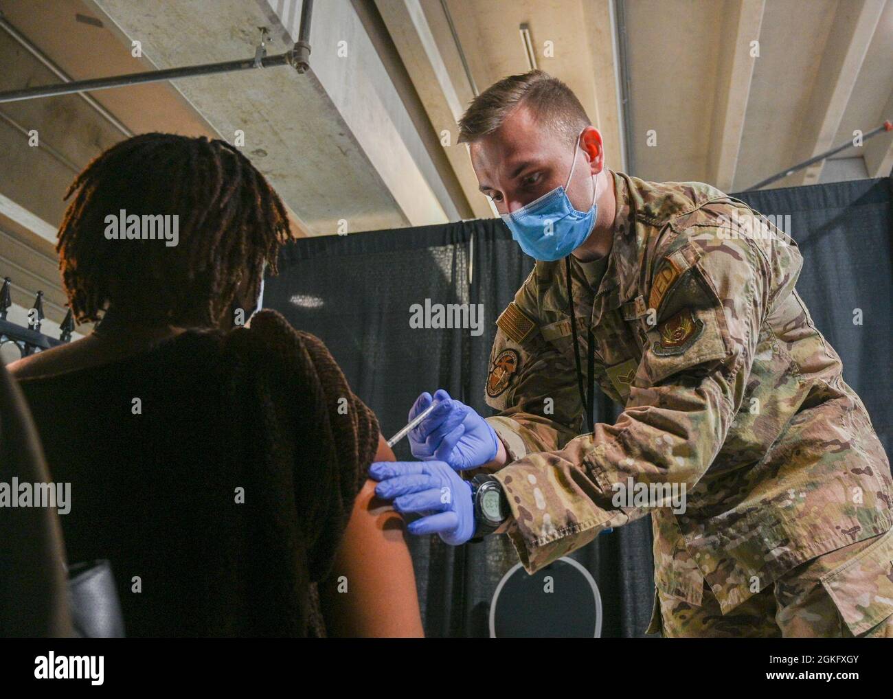 U.S. Air Force Senior Airman Jake Tyner, a Carbondale, Illinois, native and medical technician with the 75th Health Care Operations Squadron, 75th Material Command stationed at Hill Air Force Base, Utah, administers the COVID-19 vaccine to a community member at the state-led, federally-supported Ford Field COVID-19 Community Vaccination Center in Detroit, April 12, 2021. Tyner is part of a group of Airmen assigned to 1st Detachment, 64th Air Expeditionary Group that are assisting with the vaccination efforts. Tyner's main responsibility is supporting the local community members by administerin Stock Photo