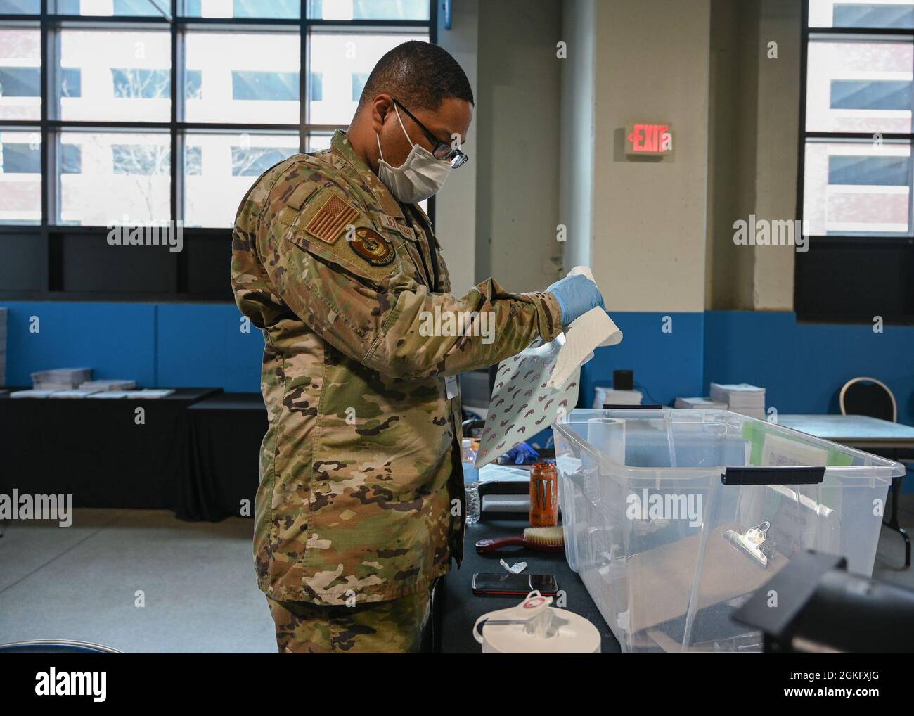 U.S. Air Force Senior Airman Dante Jefferson, a Hampton, Virginia, native and aerospace ground equipment mechanic with the 2nd Maintenance Squadron, 2nd Bomb Wing stationed at Barksdale Air Force Base, Louisiana, sanitizes clipboards for community members at the state-led, federally-supported Ford Field COVID-19 Community Vaccination Center in Detroit, April 12, 2021. Jefferson is part of a group of Airmen assigned to 1st Detachment, 64th Air Expeditionary Group that are assisting with the vaccination efforts. Jefferson is ready to provide a helping hand to the community of Detroit, especially Stock Photo