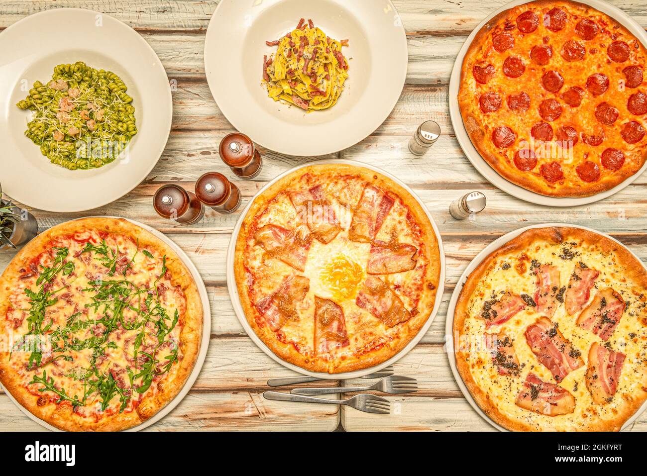 Top view of Italian pasta dishes and typical pizzas with guanciale and pepperoni on wooden table Stock Photo