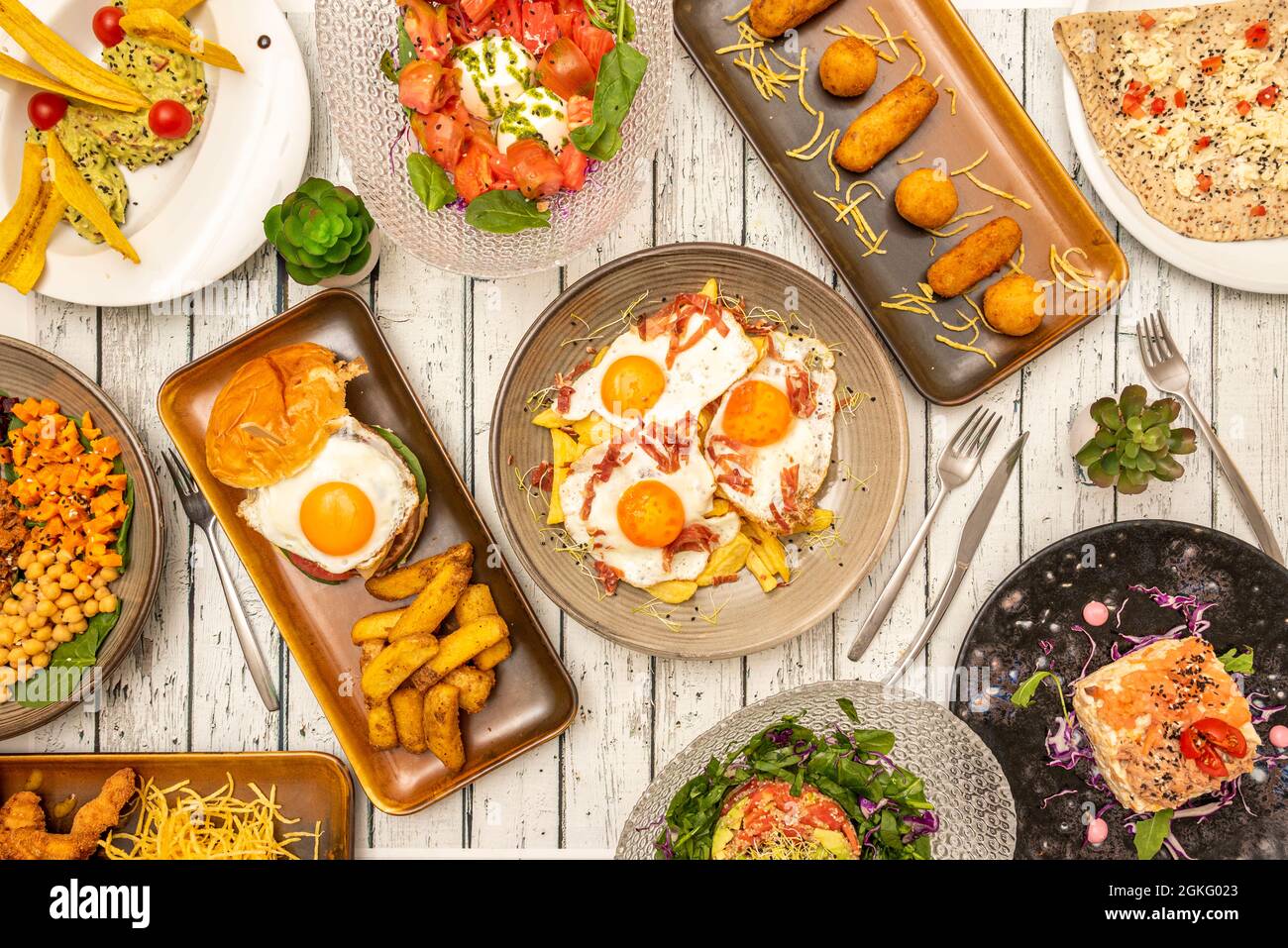 Typical Spanish tapas dishes. Goat roll salad. Roman-style battered squid, serrano ham croquettes, cheese cake Stock Photo