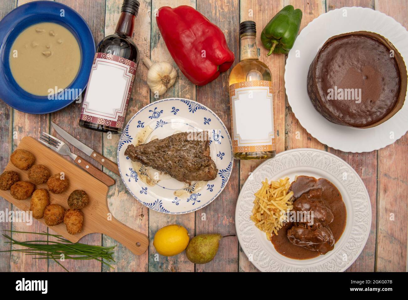 Rack of pepper with pepper, pork cheeks in wine, assorted croquettes, white and red wine, chocolate cake and cream of mushrooms. Stock Photo