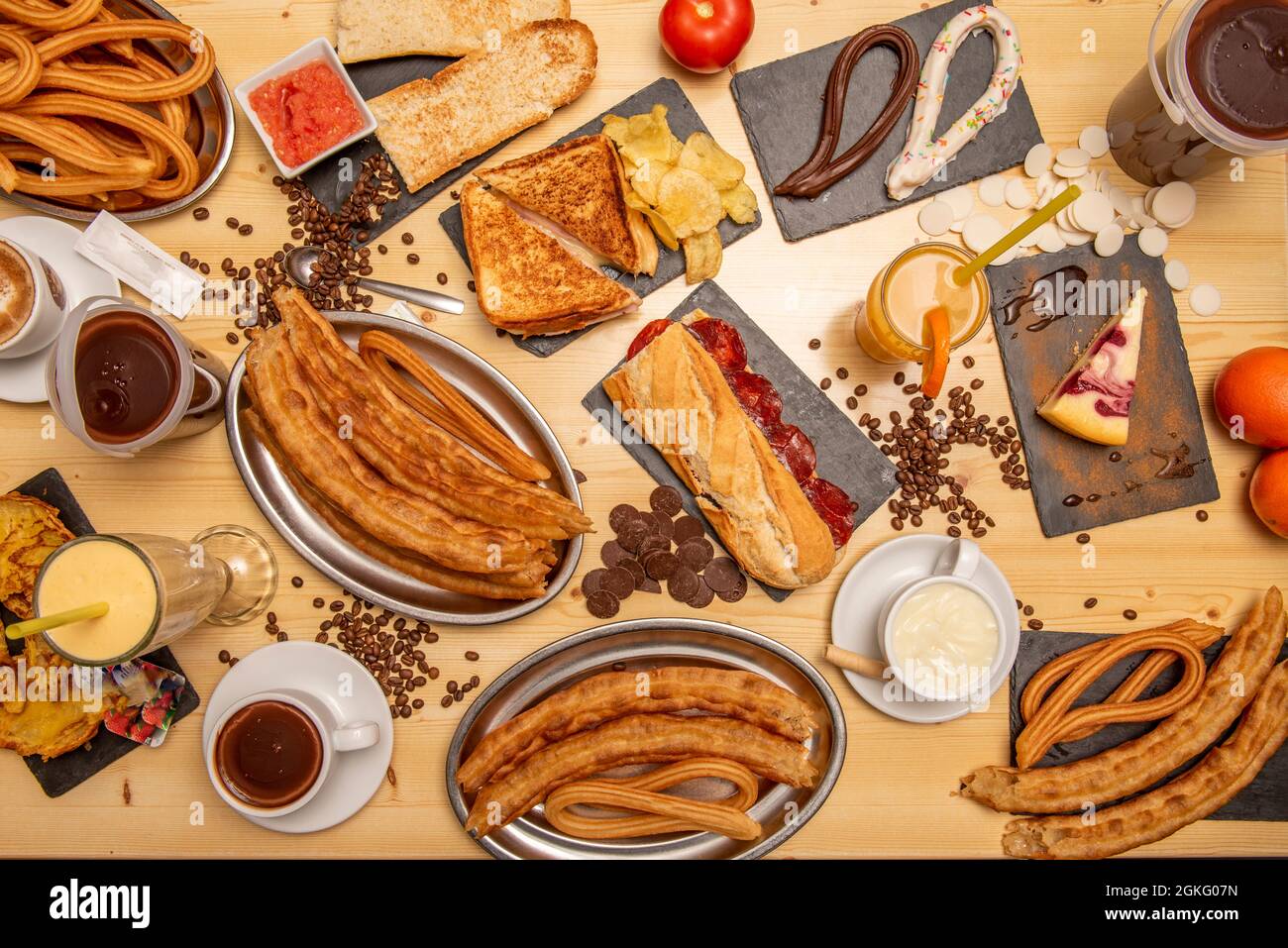 Set of dishes and sandwiches for breakfast and lunch. Biocata of chorizo, cheese sandwich and ham. Normal and chocolate churros. Orange juice, Porras Stock Photo