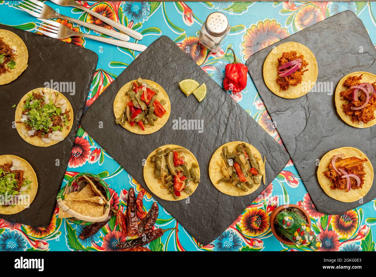Black slate trays with corn and cochinita pibil tacos, nopales tacos, al pastor tacos and corn nachos Stock Photo