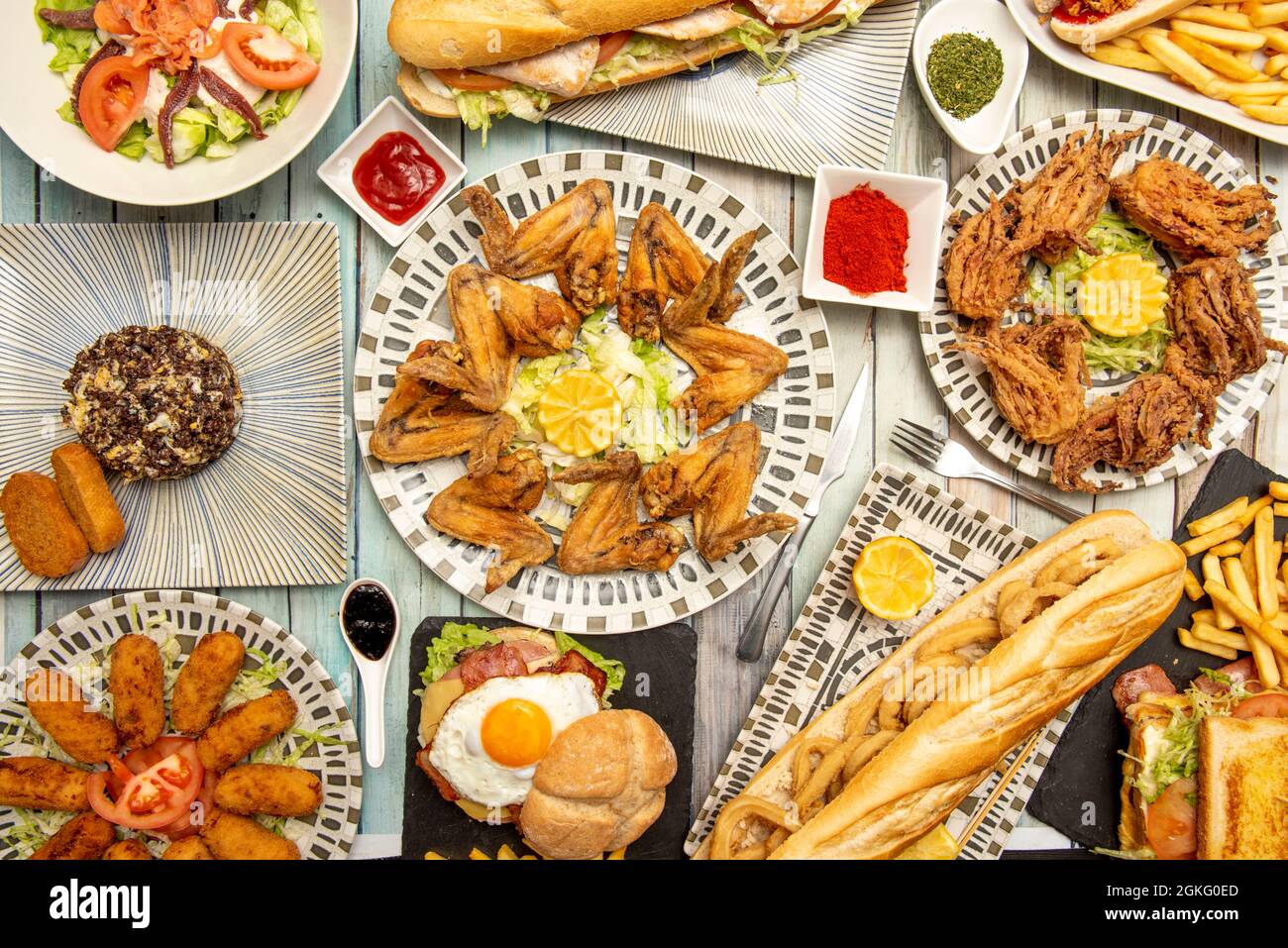 Set of typical dishes served in a Spanish tea restaurant with fried chicken wings with lemon, fried battered rabas, beast squid rings sandwich, ham cr Stock Photo