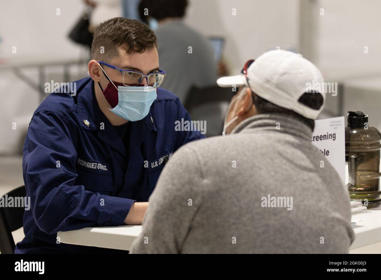 U.S. Coast Guard Petty Officer 3rd Class Alberto Rodriguez-Strazicic, a Mahwah, New Jersey native assigned to the U.S. Coast Guard Sector Virginia, screens a community member at the federally-run pilot Community Vaccination Center in Greenbelt, Maryland, April 13, 2021. U.S. Northern Command, through U.S. Army North, remains committed to providing continued, flexible Department of Defense support to the Federal Emergency Management Agency as part of the whole-of-government response to COVID-19. Stock Photo