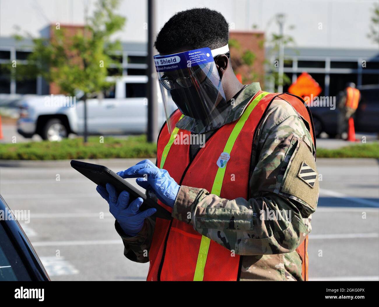 U.S. Army Spc. Rashad Kelley, a unit supply specialist with the Savannah-based Headquarters and Headquarters Battery, 1st Battalion, 118th Field Artillery Regiment, 48th Infantry Brigade Combat Team, Georgia Army National Guard receives a visitor April 13, 2021, at a mass vaccination site in Savannah, Georgia. The Georgia National Guard provided on-site logistics and operation support to the Georgia Emergency Management and Homeland Security Agency as they administered COVID-19 vaccinations at mass vaccination locations across Georgia. Stock Photo