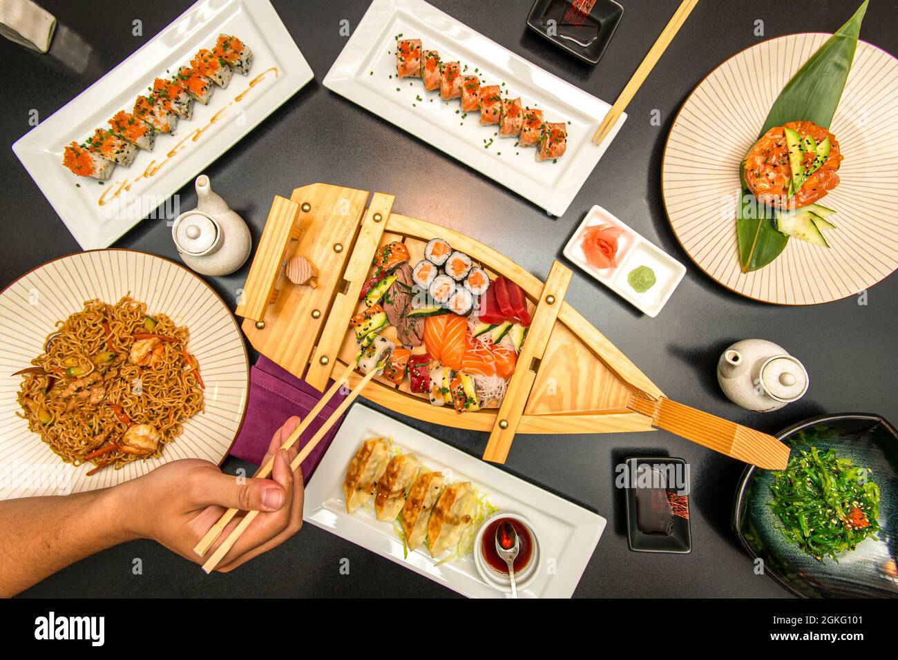 Set of Japanese dishes and sushi on black table. Salmon nigiri, red tuna sashimi, california roll, wakame seaweed salad, parlor tartare with avocado, Stock Photo