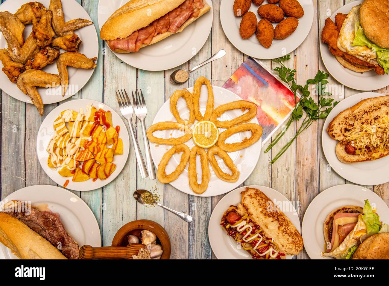 set of typical food dishes served in Spanish taverns. Squid a la romana, patatas bravas, fried wings, bacon sandwich, homemade croquettes Stock Photo
