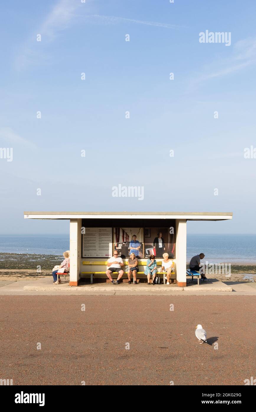 Llandudno, Conwy, UK, September 6th 2021: People sitting in the sun in a shelter on the promenade that runs the length of Llandudno's North Shore. Stock Photo