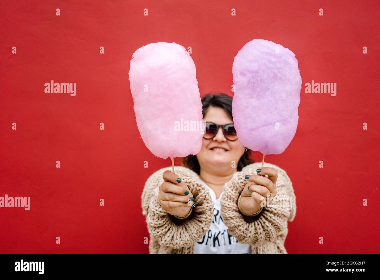 Woman with two cotton candy in her hands, she wears dark glasses. Copy space Stock Photo