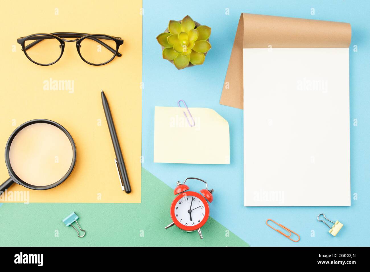 White notepad glasses pencil on blue background Stock Photo