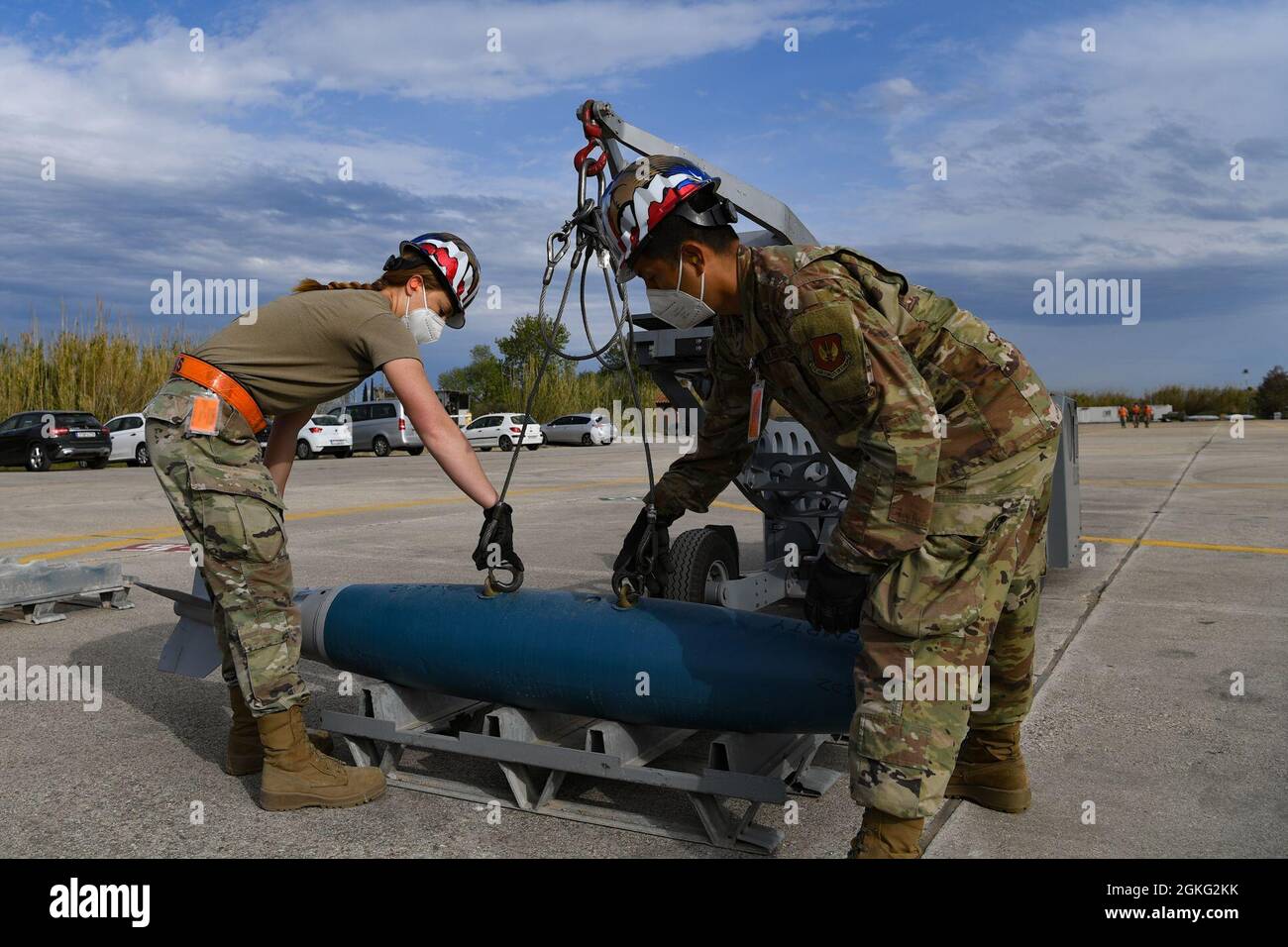 U.S. Airmen with the 31st Munitions Squadron (MUNS) hook an inert bomb onto a bomb lift at Andravida Air Base, Greece, April 13, 2021. The 31st MUNS, along with other units from the 31st Fighter Wing, participated in INIOCHOS 21, a Hellenic air force-led, joint force exercise. Stock Photo