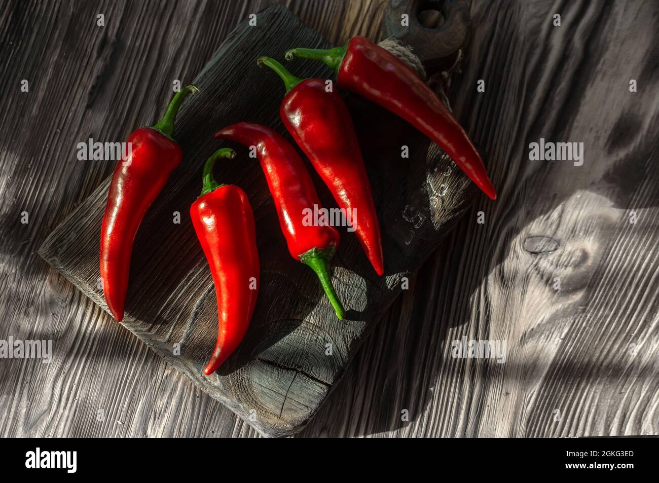 chili pepper on a textured wooden background. Ripe red pepper is lying on a wooden table in the closet, ready to dry. rustic style, a copy of the spac Stock Photo