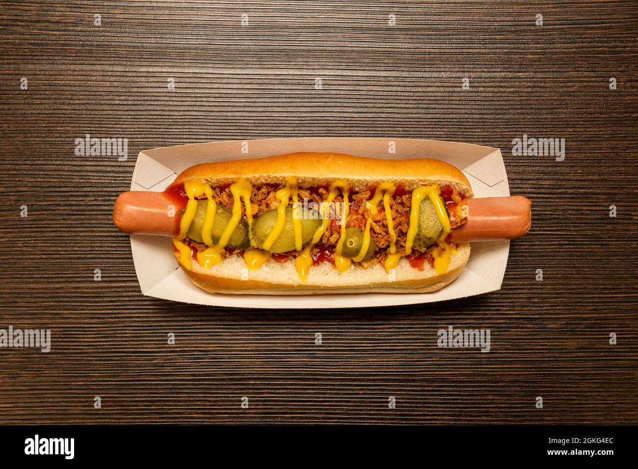 top view image of hot dog with pickles, cooked sausage, ketchup, mustard and crispy onion on cardboard tray Stock Photo