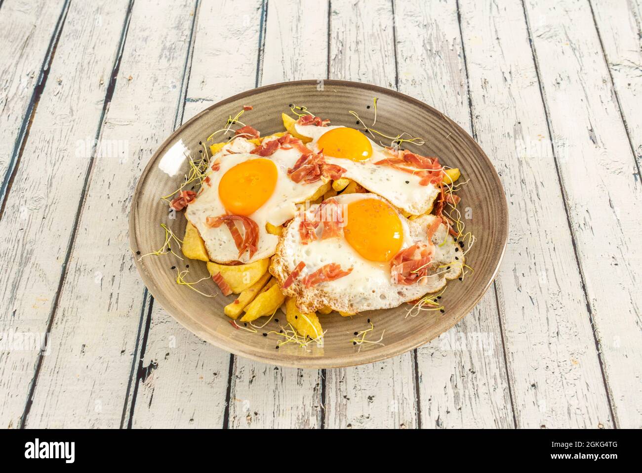 Delicious typical Spanish dish to share with broken eggs, ham slices