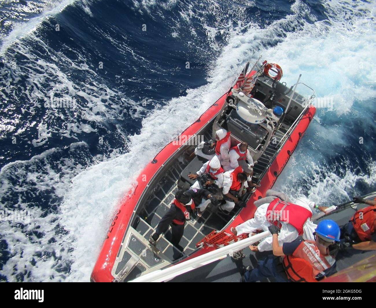 Coast Guard Cutter Joseph Napier crewmembers work to repatriate 15 illegal migrants, 12 men and three women, to the Dominican Republic Navy patrol boat (Capella-108) in waters just off the Dominican Republic April 14, 2021.  The Coast Guard Cutter Paul Clark interdicted the migrant group the evening of April 13, 2021 aboard a makeshift vessel in the Mona Passage. Stock Photo