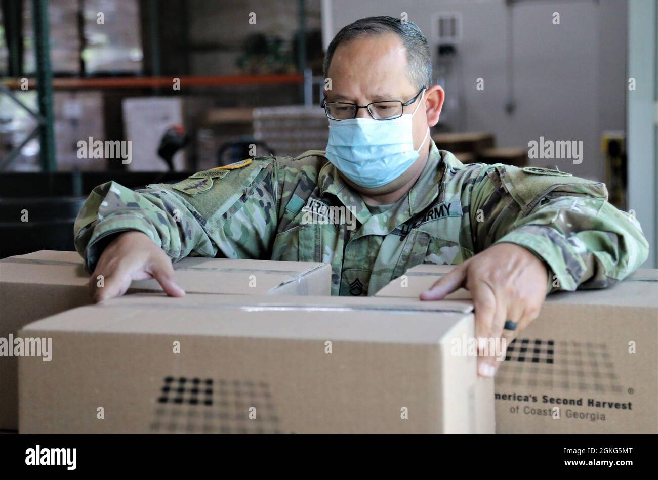 U.S. Army Staff Sgt. David Gurule, a parachute rigger with the Marietta-based 165th Quartermaster Company, 781st Troop Command Battalion, 78th Troop Command, Georgia Army National Guard stacks a box of food April 14, 2021, at America’s Second Harvest of Coastal Georgia food bank in Savannah, Georgia. Georgia Guardsmen provided support to food banks across the state to help citizens in need during the COVID-19 pandemic. Stock Photo