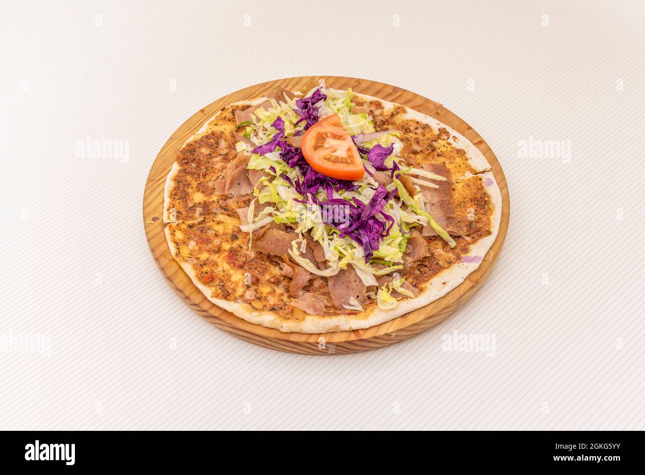 Arab kebab pizza, lahmacun with purple cabbage, tomato, grated iceberg lettuce on wooden plate. Stock Photo