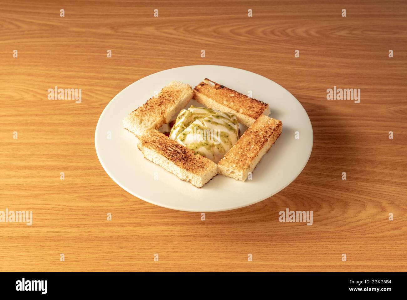 image of burrata with pesto sauce accompanied by pieces of toast Stock Photo