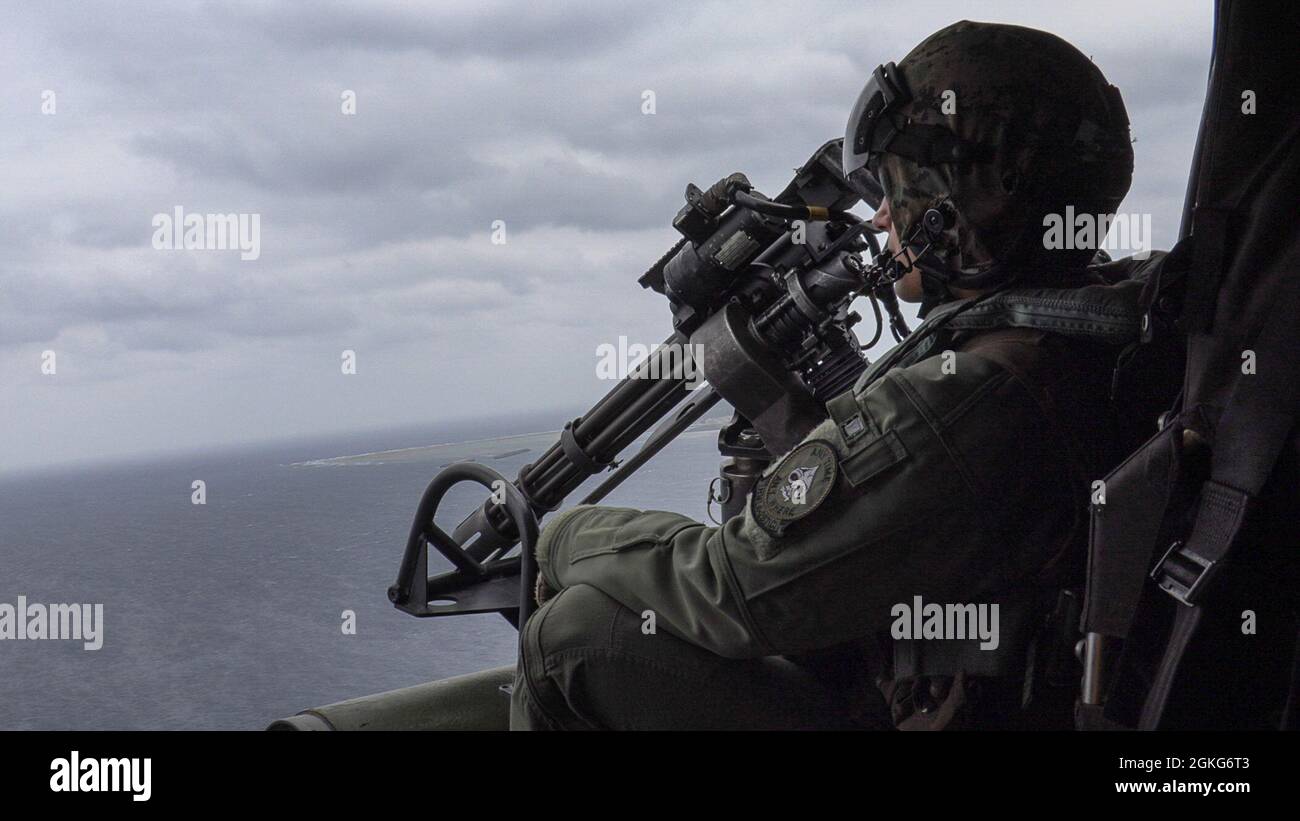 U.S. Marine Corps Cpl. Brooks Krockover, a UH-1Y Venom crew chief with Marine Light Attack Helicopter Squadron (HMLA) 267, observes the range area during live-fire training as part of a mission rehearsal exercise (MRX) off the coast of Okinawa, Japan, April 14, 2021. The MRX served as a culminating event for HMLA-267 as they near the end of their time in Okinawa as part of the Unit Deployment Program. Stock Photo
