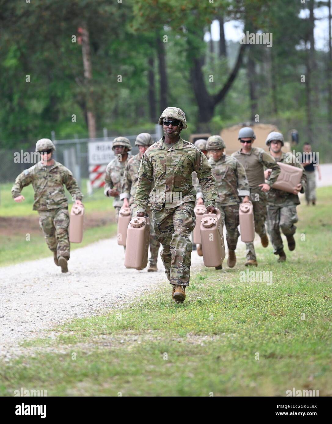 Soldiers from Support Battalion, 1st Special Warfare Training Group (Airborne) carry water cans as part of a stress-shoot during the battalion's Commander's Cup competition at Fort Bragg, North Carolina April 15, 2021. The Soldiers from each company competed in a ruck march, obstacle course, land navigation, Jeopardy-themed trivia contest and stress shoot with pistols and rifles. Stock Photo