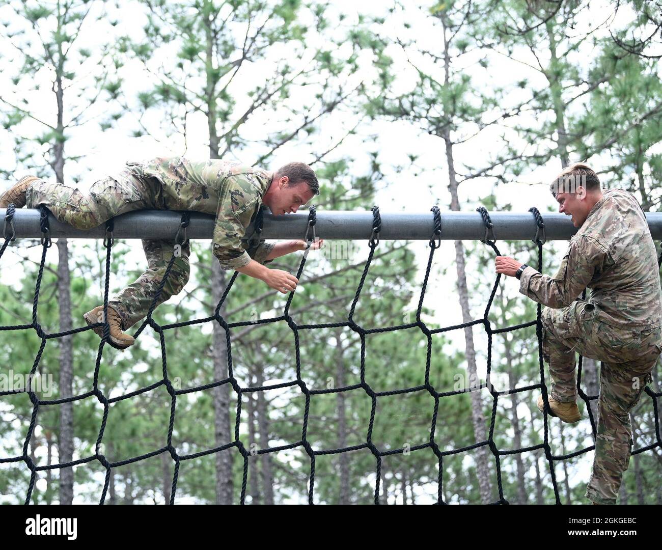 Soldiers from Support Battalion, 1st Special Warfare Training Group (Airborne) climb a cargo net during the battalion's Commander's Cup competition at Fort Bragg, North Carolina April 15, 2021. The Soldiers from each company competed in a ruck march, obstacle course, land navigation, Jeopardy-themed trivia contest and stress shoot with pistols and rifles. Stock Photo