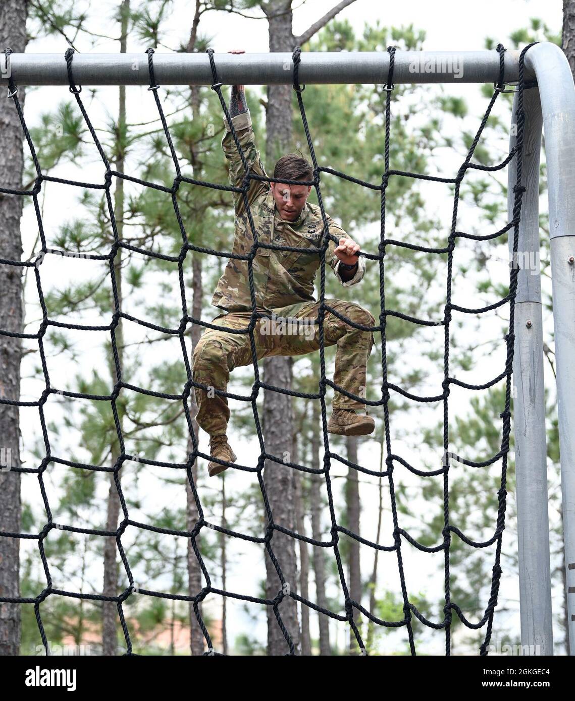 A Soldier from Support Battalion, 1st Special Warfare Training Group (Airborne) climbs a cargo net during the battalion's Commander's Cup competition at Fort Bragg, North Carolina April 15, 2021. The Soldiers from each company competed in a ruck march, obstacle course, land navigation, Jeopardy-themed trivia contest and stress shoot with pistols and rifles. Stock Photo