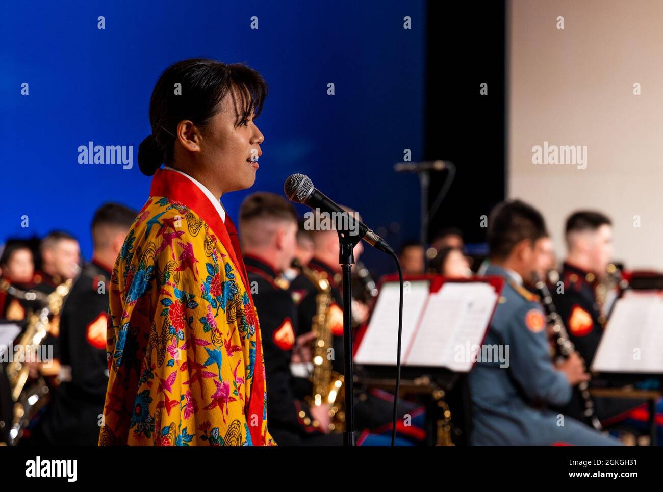Japan Ground Self-Defense Force (JGSDF) Sgt. Mio Sakuma, a french horn player with the JGSDF 15th Brigade band sings “Bashofu Bossa Nova,” an Okinawan folk song during the spring concert in Tedako Hall in Urasoe, Okinawa, Japan, April 16, 2021. The bands' harmonious performance was a display of the III Marine Expeditionary Force and 15th Brigade bands' alliance and unity within the musical arts. The annual concert was performed virtually and the recording will debut on social media platforms within the coming weeks. Sakuma is a native of Fukuoka. Stock Photo