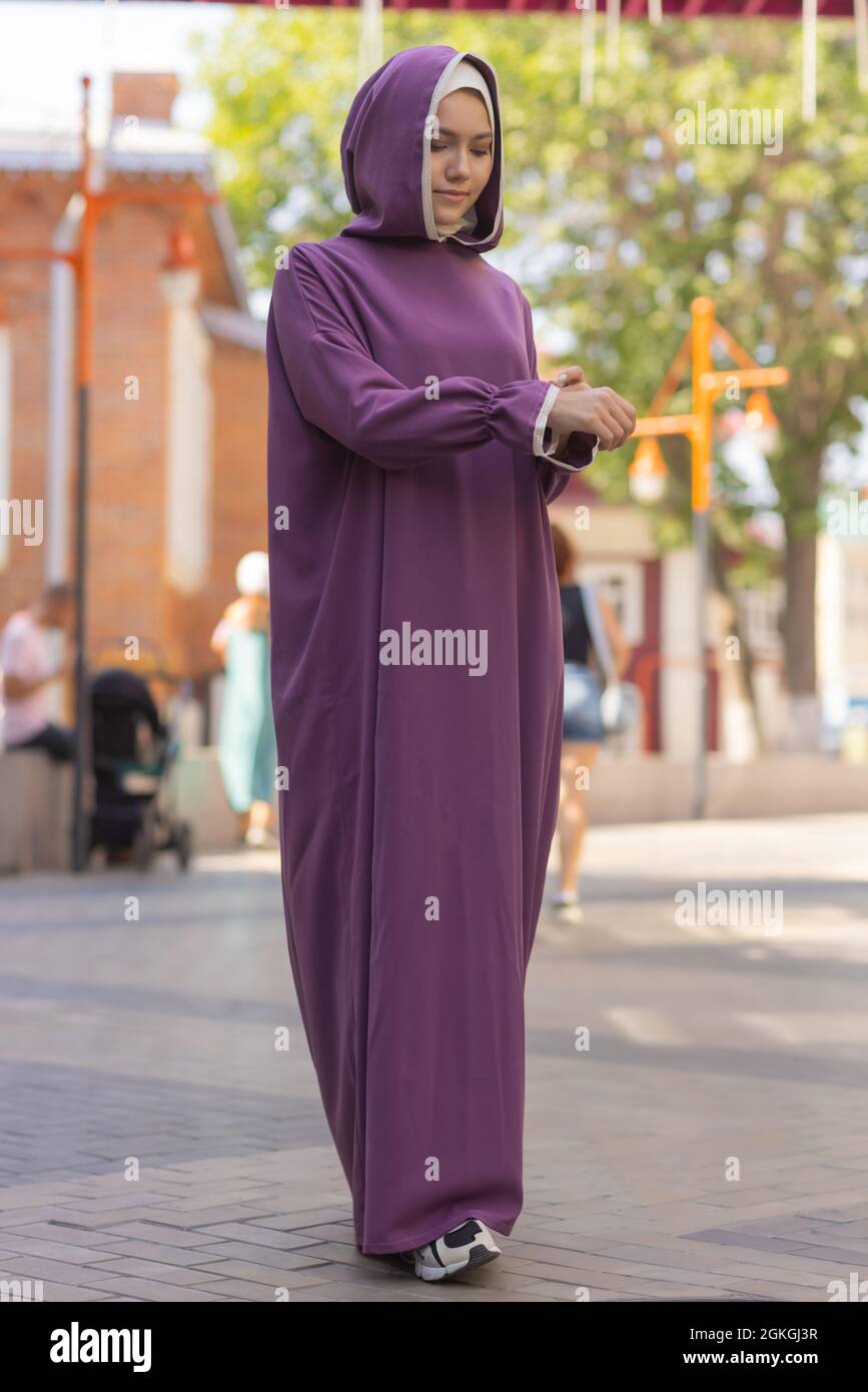 Islamic beautiful woman in a Muslim dress standing on a summer park street background forest autumn trees.world hijab day Stock Photo
