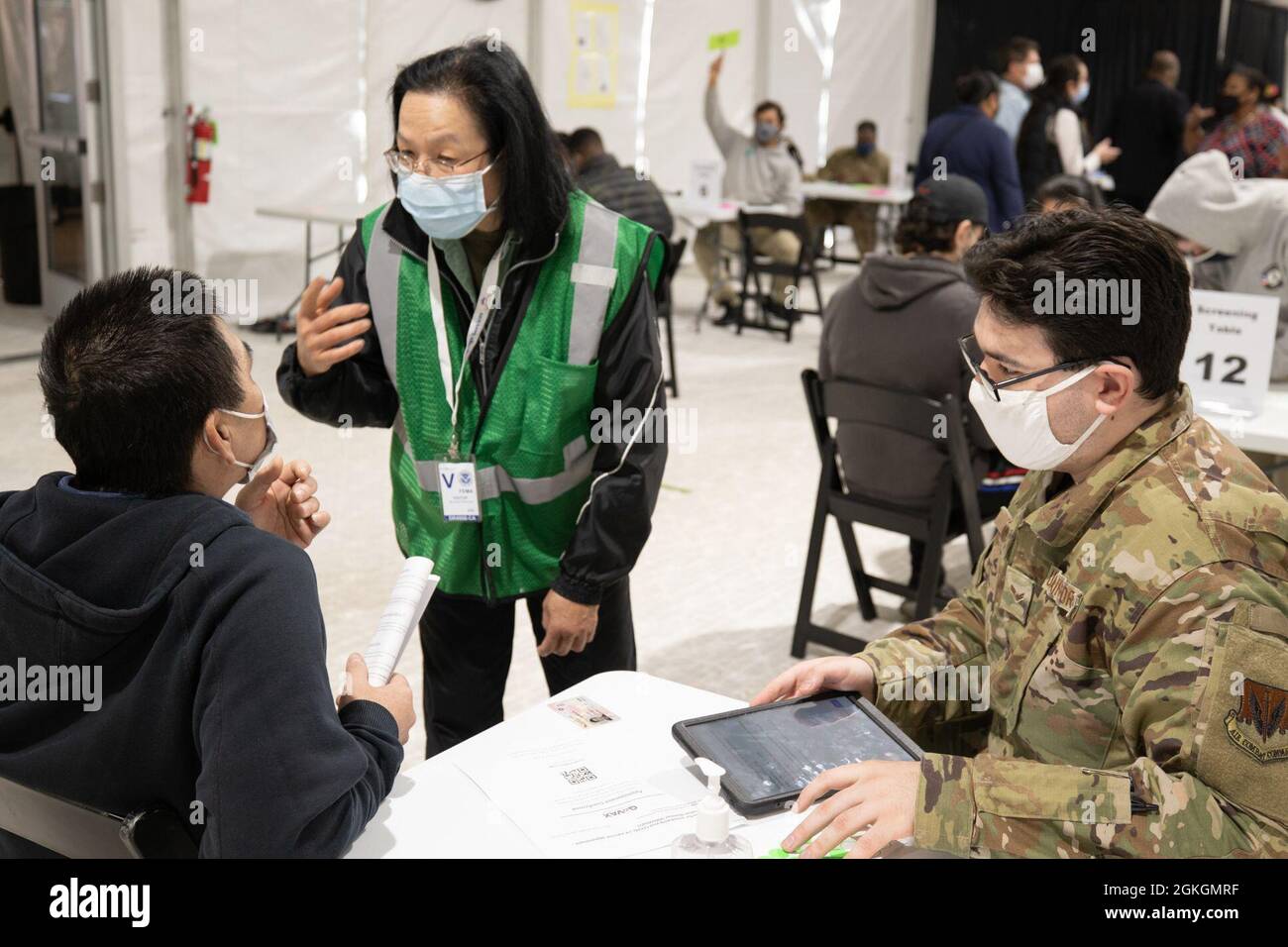 U.S. Air Force Airman 1st Class Payton Jones (right), a Princeton, Texas native and an administration specialist assigned to the 335th Air Expeditionary Group, screens a community member with Ngoc Diep Trinh, a French and Vietnamese translator with the Federal Emergency Management Agency, at the federally-run pilot community vaccination center in Greenbelt, Maryland, April 17, 2021. U.S. Northern Command, through U.S. Army North, remains committed to providing continued, flexible Department of Defense support to FEMA as part of the whole-of-government response to COVID-19. Stock Photo