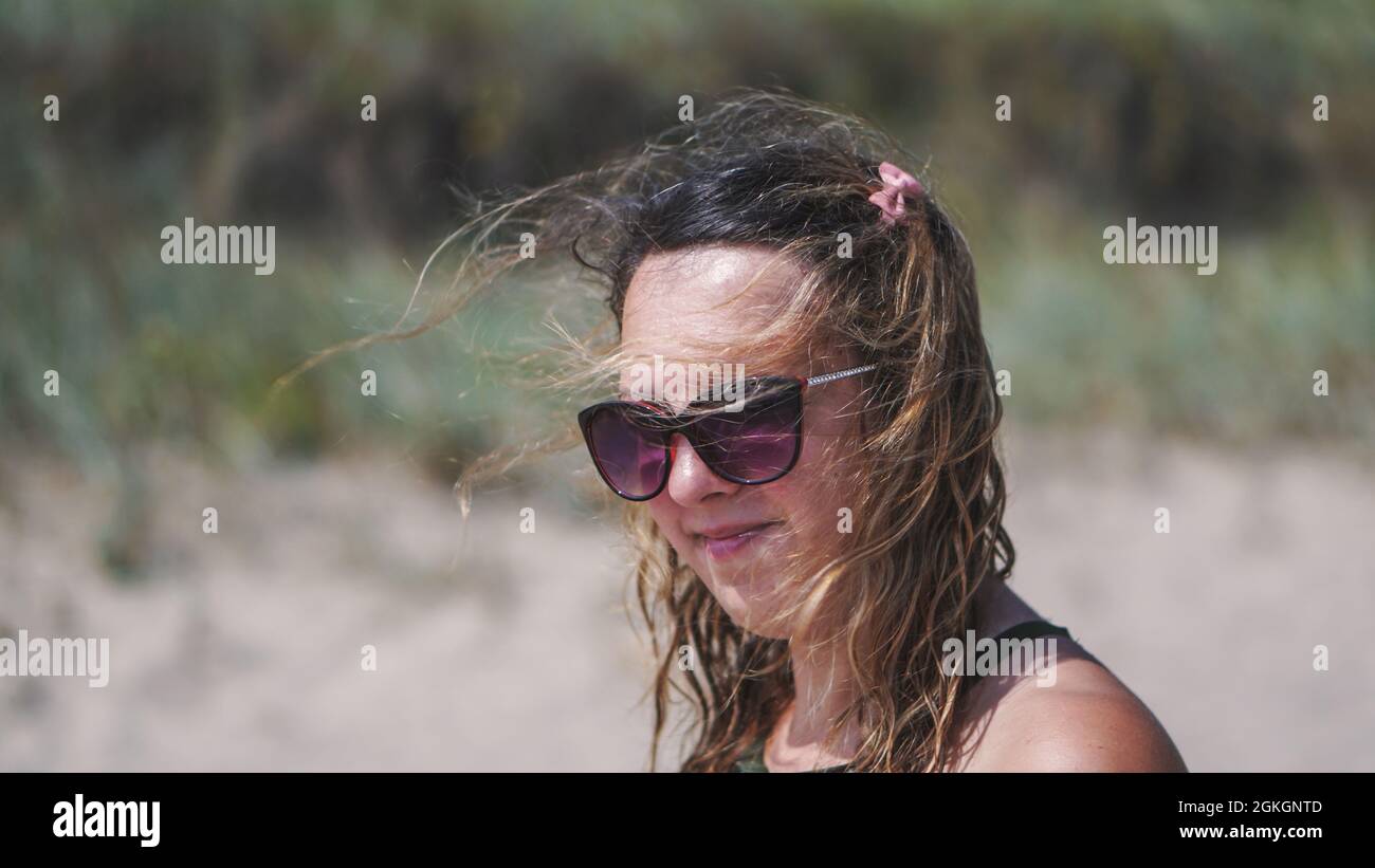 An authentic portrait of an attractive confident girl looking away from the camera. Closeup side view of a young natural happy woman on the beach. Stock Photo