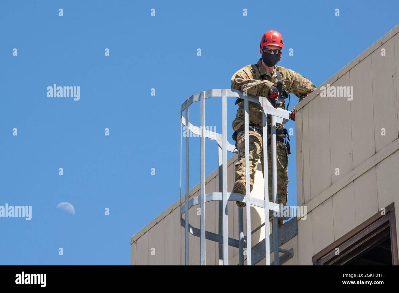 U.S. Air Force Staff. Sgt. Daniel Robinson, 60th Civil Engineer Squadron lead firefighter, climbs a ladder that leads to the roof of the structure used to train fire protection personnel April 19, 2021, at the Travis Fire and Emergency Services training facility at Travis Air Force Base, California. The training demonstration provided senior leadership with a clear picture of the technical rescue capabilities for multi-story building and confined space rescues conducted by Travis AFB emergency response personnel. Stock Photo