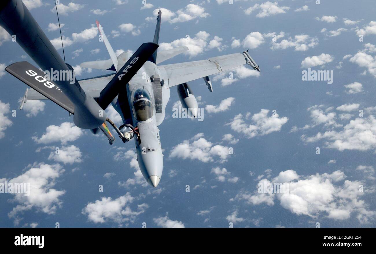 A U.S. Marine Corps F/A-18C Hornet aircraft from Marine Fighter Attack Squadron 232 out of Marine Corps Air Station Iwakuni, Japan, conducts aerial refueling with a 909th Air Refueling Squadron KC-135 Stratotanker from Kadena Air Base, Japan, over the Pacific Ocean, Apr. 20, 2021. The Air Force and Marine Corps frequently conduct joint training operations in the Pacific to maintain high standards of proficiency and continue to demonstrate our commitment to the U.S-Japan Treaty of Mutual Security and Cooperation. Stock Photo