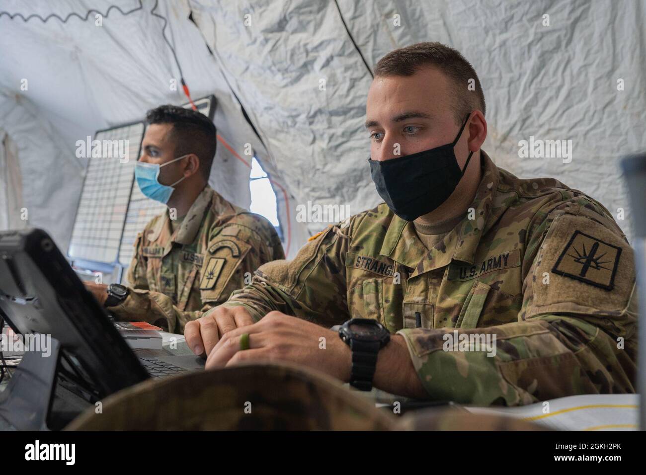U.S. Army Sgt. Nakalunk, the property book non-commissioned officer, and 1st Lt. Nathan Strange, engineer officer and platoon leader, both assigned to Headquarters Company 204th Engineer Battalion, 153rd Troop Command Brigade, 53rd Troop Command, work on their laptops at Regional Support Camp Panther, North Vernon, Ind., April 20, 2021. Nakalunk and Strange work in the Army Logistics Operations Center. NY National Guard Soldiers provide operational and logistical support to other state National Guard battalions during the Guardian Response Exercise 21 Indiana. Stock Photo