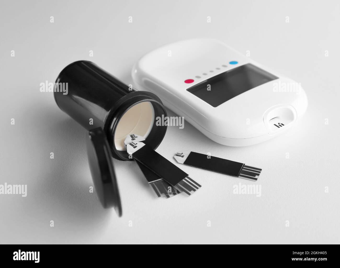 Digital glucose meter and test strips on white background stock photo