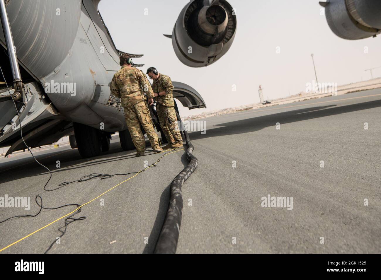 U.S. Air Force Staff Sgt. Roberto Barraza, loadmaster for the 816th Expeditionary Airlift Squadron, and U.S. Air Force Tech. Sgt. Shane Thaxton, an evaluator loadmaster for the 816th EAS, attach a fuel hose for C-17 Globemaster III hot refueling operations during a training and certification mission at Al Udeid Air Base, Qatar, April 9, 2021. The 816th EAS and 379th Expeditionary Logistics Readiness Squadron Airmen performed multiple iterations of a process where the Aerial Bulk Fuel Delivery System was drained into an R-11 fuel truck, then C-17 Globemaster III engines were left running for ho Stock Photo