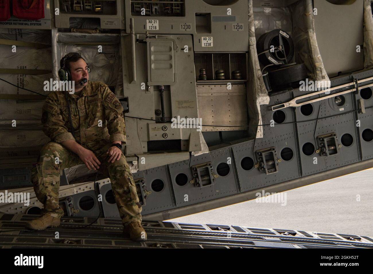 U.S. Air Force Staff Sgt. Jason Conner, instructor loadmaster for the 816th Expeditionary Airlift Squadron, monitors communications during C-17 Globemaster III hot refueling operations for a training and certification mission at Al Udeid Air Base, Qatar, April 9, 2021. The 816th EAS and 379th Expeditionary Logistics Readiness Squadron Airmen performed multiple iterations of a process where the Aerial Bulk Fuel Delivery System was drained into an R-11 fuel truck, then the engines were left running for hot refueling from the truck to the aircraft, as well as a defueling process from the plane ba Stock Photo